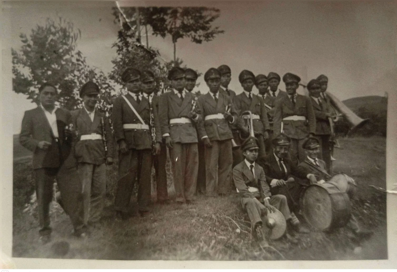 Antigua formación de músicos con instrumentos de viento y percusión en un entorno rural.
